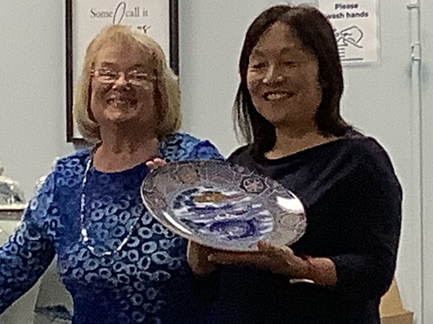 Two women holding a plate in front of them.