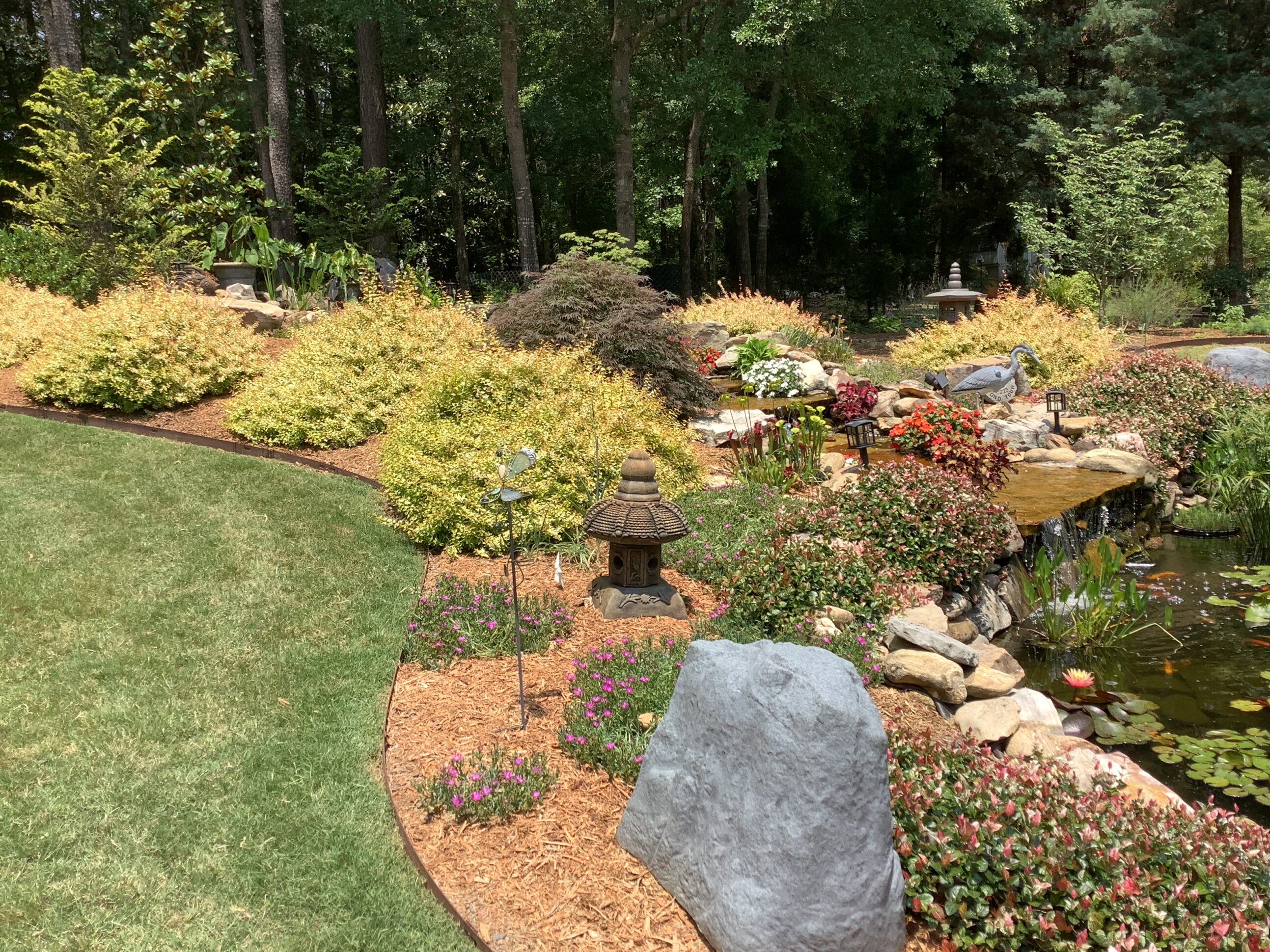 A garden with rocks and trees in the background.