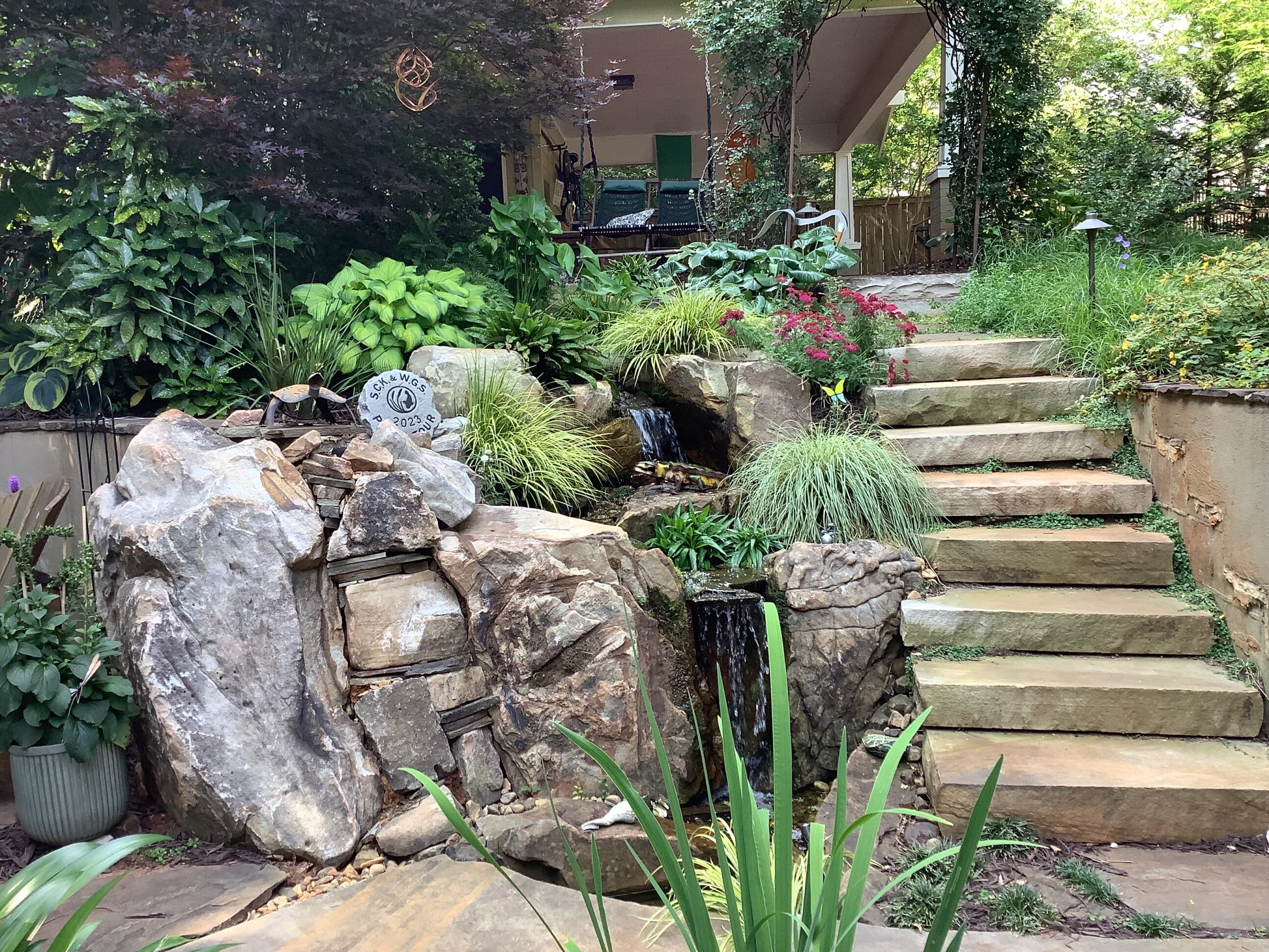 A garden with rocks and stairs leading to the house.