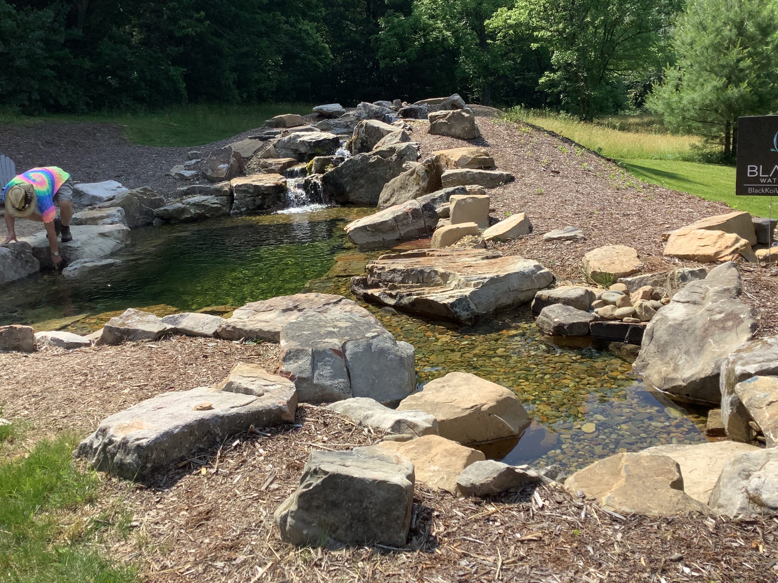 A pond with rocks and water running down it.