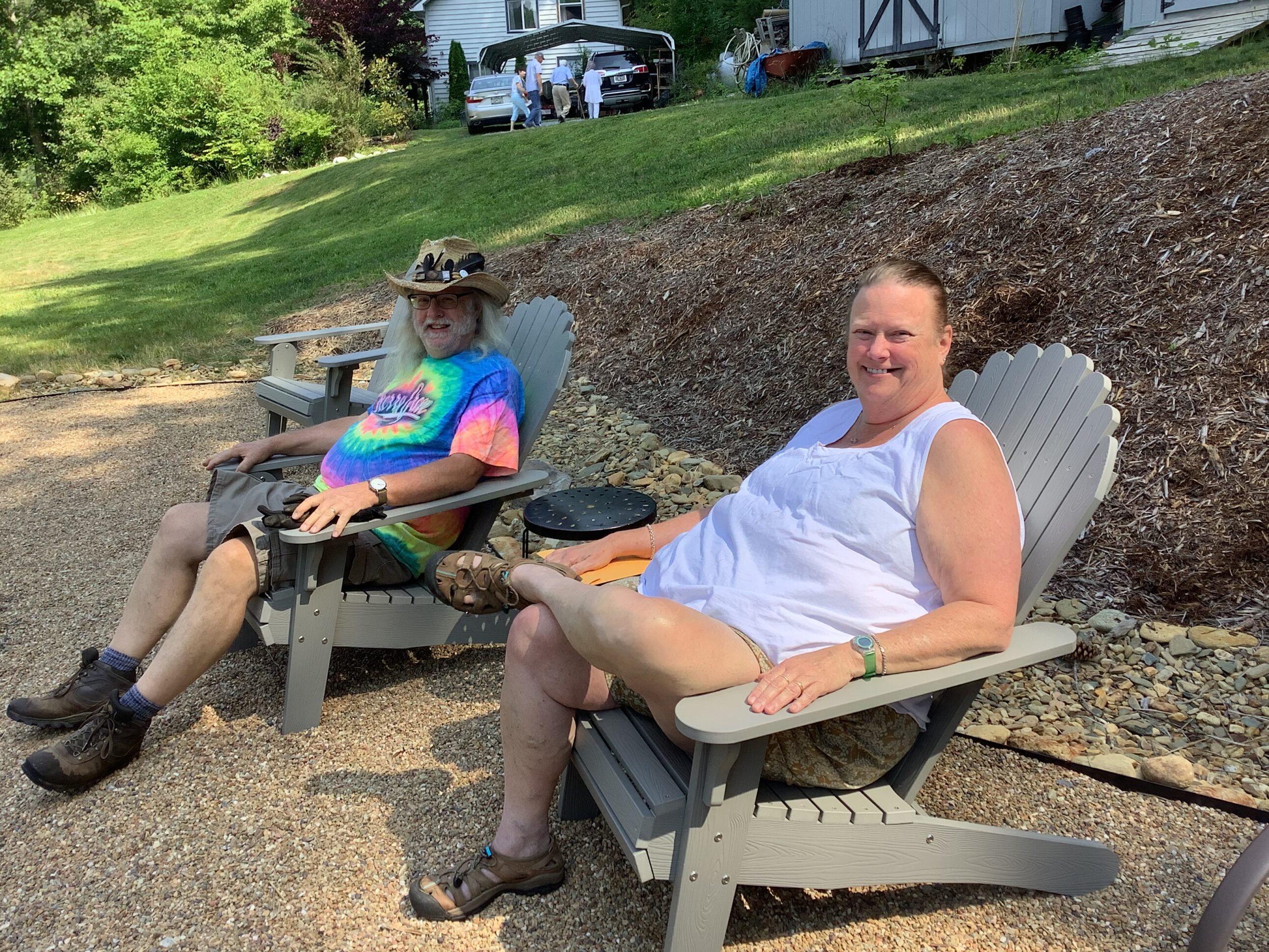 Two people sitting in lawn chairs on a gravel path.